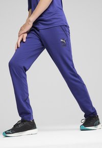 Fialové športové nohavice so slim fit, s čiernymi detailmi a logom vpredu. Mäkká látka s hladkou textúrou a zúženými nohavicami.