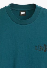 Tyrkysové tričko s kulatým výstřihem, uvnitř límce černá visačka a stylizované černé grafické logo na levé hrudi s nápisem "Levi's."