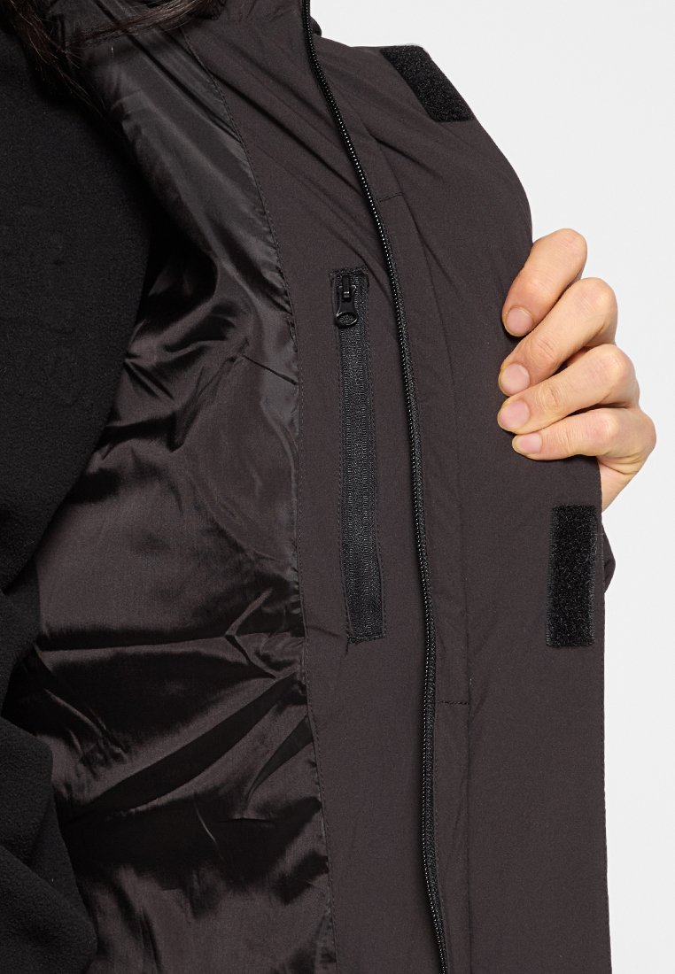 Veste noire avec une poche zippée et des accents en Velcro. L'intérieur a une texture lisse avec une finition brillante.