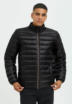 Schwarze Pufferjacke mit horizontalen Nähten, hohem Kragen, Reißverschluss vorne und seitlichen Taschen. Hergestellt aus glattem, glänzendem Stoff.