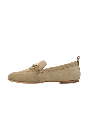 Mocasines de ante beige con suela plana, punta redondeada y una correa decorativa con una pequeña hebilla metálica. Superficie texturizada y diseño minimalista.