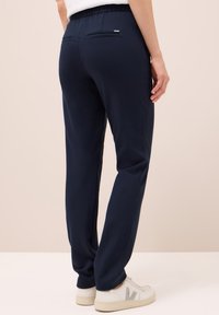 Mörkblå sweatpants med mjuk textur, elastisk midja och två bakfickor. Stylad med ljusa sneakers.