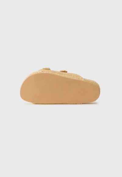 Sandale d'extérieur beige avec une semelle en caoutchouc, une tige texturée et des sangles ajustables. La semelle présente des rainures horizontales pour offrir une meilleure adhérence.