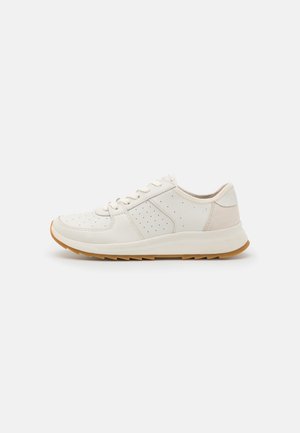 White low-top sneaker with perforated sides, lace-up front, cushioned sole, and light brown rubber outsole, shown in left profile on plain background.