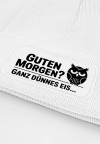 White knitted beanie featuring a rectangular patch with black text: "GUTEN MORGEN? GANZ DÜNNES EIS..." and an owl graphic.