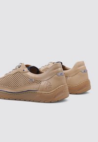 Zapatillas de piel perforada en beige con suela de goma, que presentan acentos en azul y rojo, y detalles del logo en relieve en el talón.