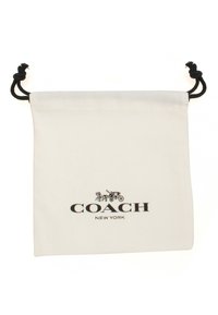 Canvas drawstring pouch, white with black cord; features "COACH NEW YORK" logo in black, simple rectangular shape, smooth texture.
