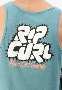 Majica bez rukava u tirkiznoj boji s podebljanim bijelim tekstom "RIP CURL" u crnom obrubu i manjim narančastim tekstom "Hard Core Surfing" na leđima.