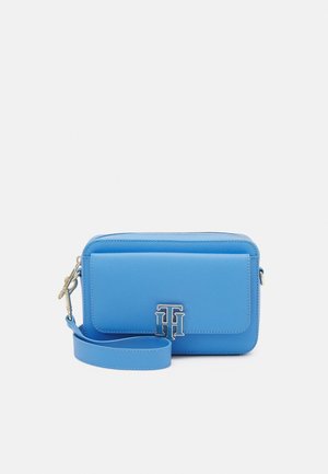 Borsa a polso in pelle blu con tasca frontale a patta e dettaglio in metallo argentato, su uno sfondo bianco semplice.