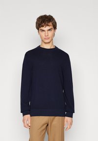 Maglione a maglia blu navy con scollatura rotonda e maniche lunghe. Presenta polsini e orlo a costine, realizzato in un tessuto liscio e strutturato.