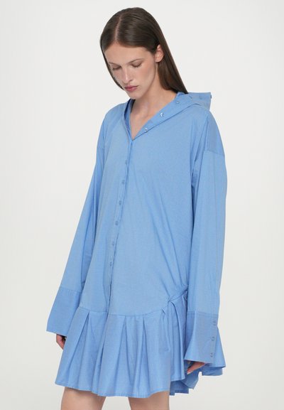 Abito camicia a scacchi blu chiaro con cappuccio, maniche lunghe, bottoni sul davanti e orlo svasato con pieghe. Tessuto morbido e testurizzato.