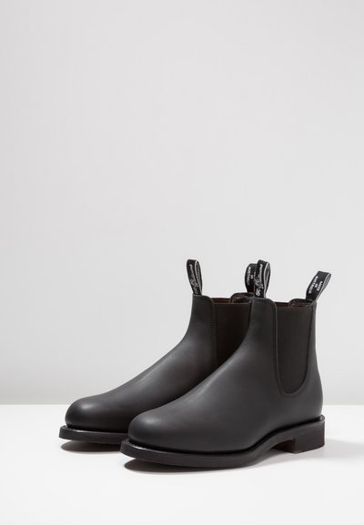 Black leather Chelsea boots feature a sleek design, elastic side panels, pull tabs, and a flat rubber sole for comfort and ease of wear.