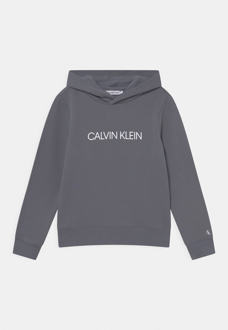 Sudadera con capucha gris que presenta un logo frontal "CALVIN KLEIN" en blanco, puños y dobladillo acanalados, con una tela suave y texturizada.