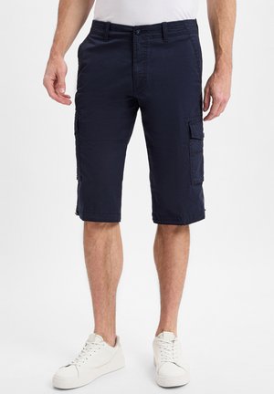 Navy Cargo-Shorts aus leichtem Stoff, mit mehreren Seitentaschen und einem knielangen Design, kombiniert mit weißen Sneakers.