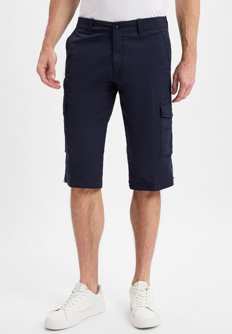 Navy Cargo-Shorts aus leichtem Stoff, mit mehreren Seitentaschen und einem knielangen Design, kombiniert mit weißen Sneakers.