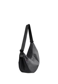 Sac bandoulière noir avec sangle réglable et petite étiquette colorée, en tissu lisse et arrondi en bas.