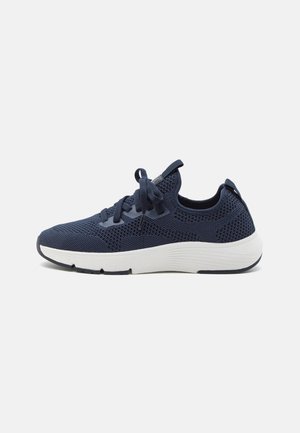 Granatowy, dziergany sneaker z sznurowaniem z przodu, białą amortyzowaną podeszwą oraz pętlami do ściągania na języku i pięcie, pokazany z profilu na jednolitym tle.