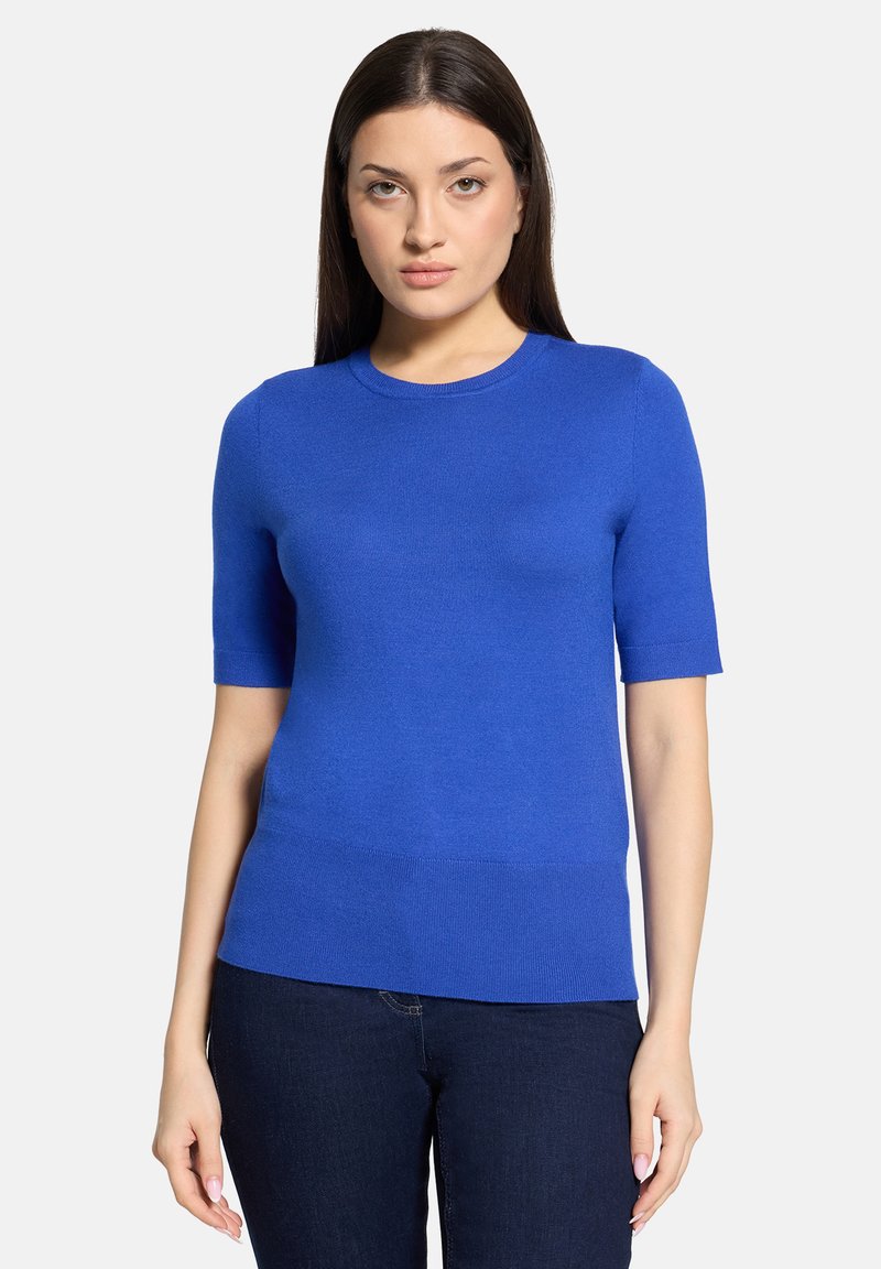 Blauer Pullover mit kurzen Ärmeln aus einem glatt gestrickten Stoff. Verfügt über einen runden Ausschnitt und eine figurbetonte Silhouette. Kombiniert mit dunklen Jeans.