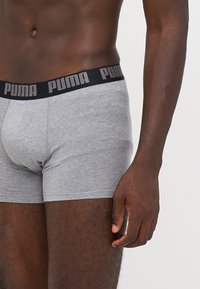 Szürke pamut boxer alsó, fekete derékvonallal, amelyen szürke Puma logó található. Az anyag lágy és sima tapintású.