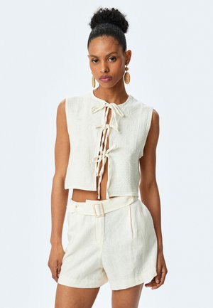 Haut court blanc avec un motif texturé et une fermeture à nouer à l'avant, associé à un short taille haute assorti, le tout en tissu léger.