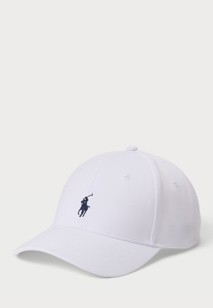 White cotton cap with a curved brim, featuring a small navy blue embroidered polo player logo on the front. Four ventilation holes on top.