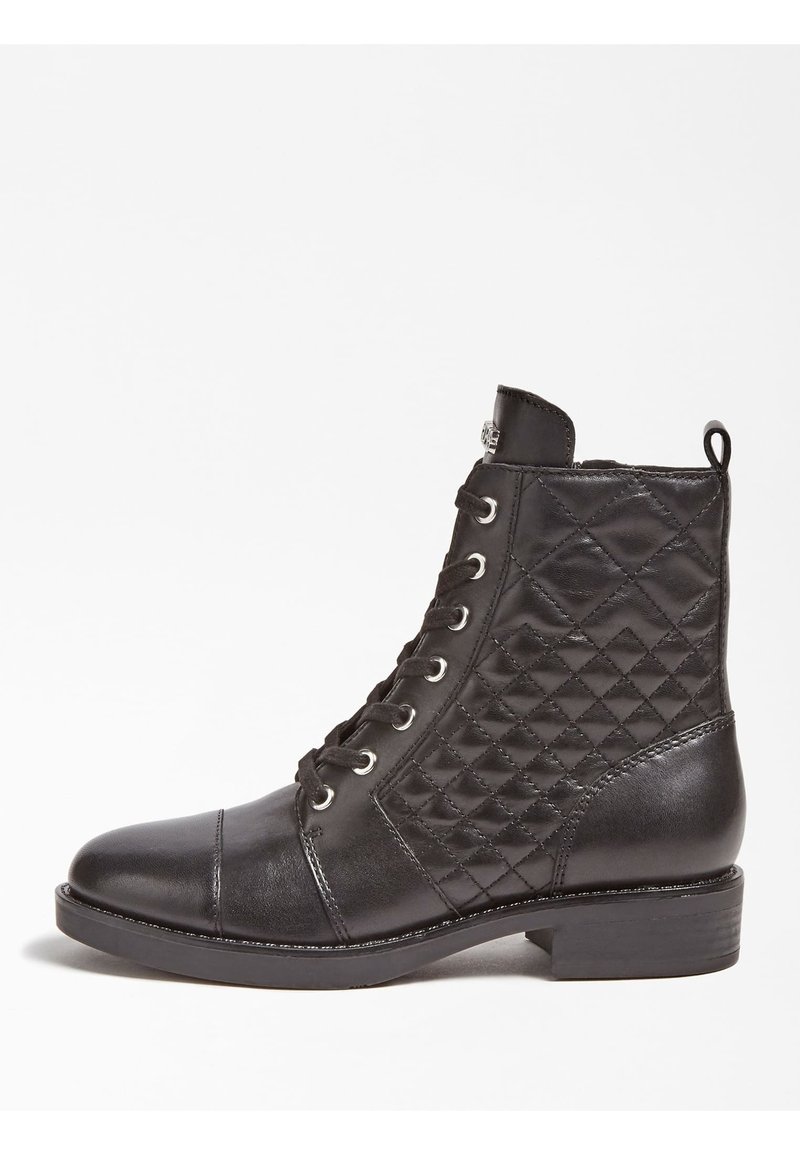 Botte cheville en cuir noir avec design matelassé, bout rond, lacets à l'avant et talon bloc bas. Présente des œillets argentés et une languette de tirage.