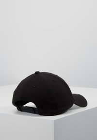 Svart baseballcaps med buet skygge, laget av teksturert stoff, med snapback-lukking og ventilasjonsåpninger.