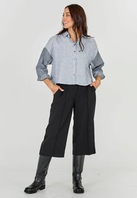 Gray and striped button-up blouse with a cropped design, paired with wide black trousers and knee-high black boots. Smooth textures.