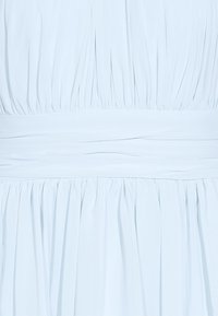 Tissu plissé bleu clair avec une large ceinture froncée créant un effet superposé et texturé.