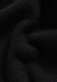 Schwarzer Wollstoff mit einer weichen, strukturierten Oberfläche. Das Material wirkt engmaschig und zeigt subtile Variationen in der Dicke.