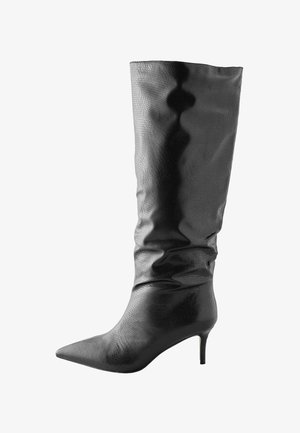 Knee-high juoda oda batai su tekstūruotu raštu, smailiu nosiu ir stiletto kulnu. Priklausantis dizainas pagerina bendrą siluetą.
