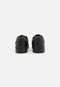 Black leather sneakers with a smooth texture, featuring a low profile, round heel, and padding at the collar for comfort.