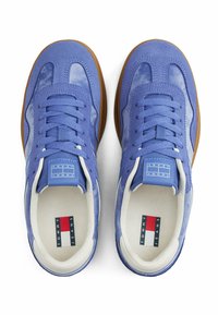 Ein Paar blaue Wildleder- und Mesh-Sneaker mit weißem Innenfutter und braunen Sohlen, ausgestattet mit dem Tommy Jeans-Logo auf den Innensohlen und den Zungenlabels.