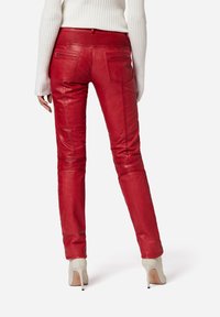 Rode leren broek met een slim fit, voorzien van ritszakken, gestructureerde tailleband en minimale stikseldetails. Draag ze met lichtgekleurde hakken.