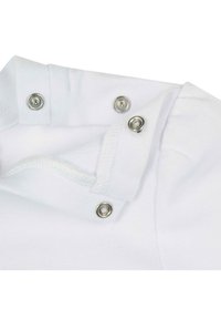 Collar de prenda de algodón blanca con broches a presión. Presenta una tela texturizada y bordes doblados. Los broches de metal plateado son visibles.
