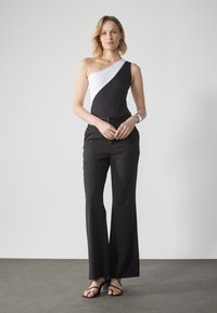 Asymmetrisk bodysuit i svart og hvitt, kombinert med svarte bukser. Elegant, tettsittende design med utsvingt ben og minimalistiske detaljer.