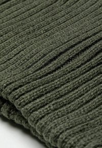Tessuto a maglia verde scuro con texture a coste verticali, che mette in evidenza un materiale morbido e spesso. I bordi piegati e le fibre visibili aggiungono dettagli.