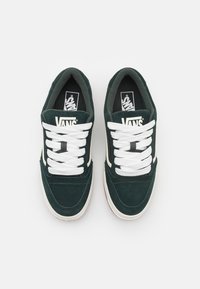 Zapatillas de ante verde oscuro con cordones blancos y la marca Vans en la lengüeta. Presenta un diseño clásico de corte bajo y acentos laterales blancos.