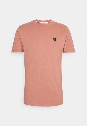 Gładki, stonowany t-shirt koralowy z krótkim rękawem i okrągłym dekoltem, z małą okrągłą czarną naszywką z logo na lewej piersi.