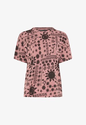 Różowy t-shirt z krótkim rękawem, ozdobiony czarnymi wzorami słońca, księżyca, gwiazdy, kwiatu i liścia ułożonymi w kompozycję przypominającą patchwork na materiale.