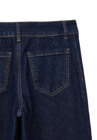 Jeans di denim blu scuro con taglio dritto, dotati di due tasche posteriori, cuciture visibili in un arancione a contrasto e una consistenza liscia.