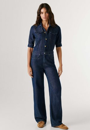 Farmer overál rövid ujjakkal, két mellzsebbel és gombos elülső résszel. Kialakítása karcsúsított derékkal és bőszárú nadrággal sötétkéklila színben.