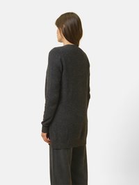 Tmavě šedý dlouhý svetr s volným střihem, kulatým výstřihem a žebrovanými manžetami. Měkká textura, délka do poloviny stehna, minimalistický design.