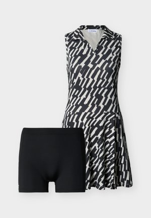 Αμάνικο φόρεμα με ασπρόμαυρο αφηρημένο σχέδιο, με γιακά και φούστα που ανοίγει προς τα κάτω· περιλαμβάνει μαύρο σορτς χωρίς σχέδιο.