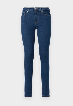 Jeans ajustados feitos de denim azul escuro. Apresentam um design justo, cintura alta, estilo de cinco bolsos e discretos detalhes de costura laranja.