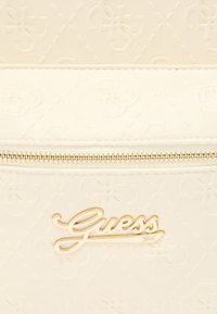 Λευκή δερμάτινη τσάντα χειρός με ανάγλυφο μοτίβο λογότυπου, κλείσιμο με φερμουάρ και χρυσή πλάκα "Guess" μπροστά.