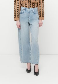 Lys blå vide bukser laget av denim med en opprevet kant, med høy midje og en avslappet passform.