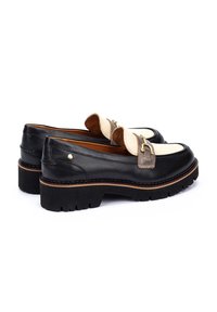 Mocasines de cuero negro con puntera en crema contrastante, con una hebilla en tono dorado y una suela gruesa con detalles texturizados.