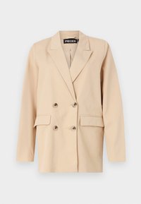 Blazer beige à double boutonnage avec revers crantés, quatre boutons en écaille de tortue et deux poches avant à rabat.
