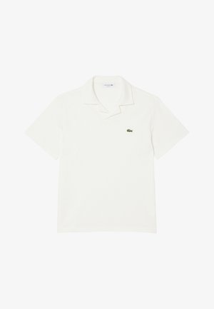 Witte polo met korte mouwen, een kraag en een klein groen krokodillenlogo op de linkerborst.
